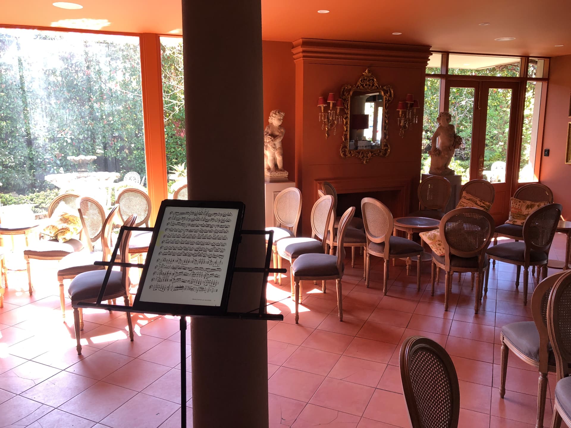 Recital room set with music stand and rows of chairs facing a fireplace