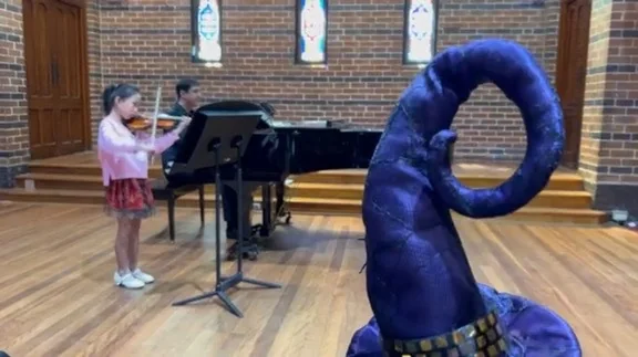 Young violinist performing with piano at a family costume concert