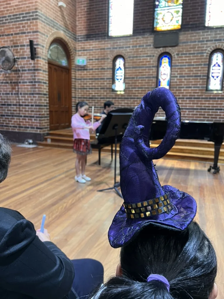Costumed audience member watching a young violinist perform