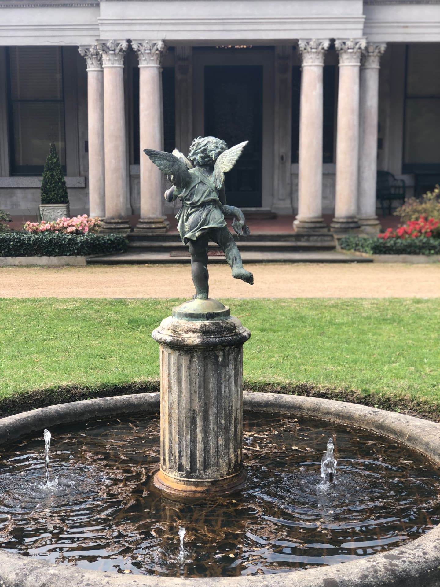 Bronze cherub fountain in front of the colonnaded entrance